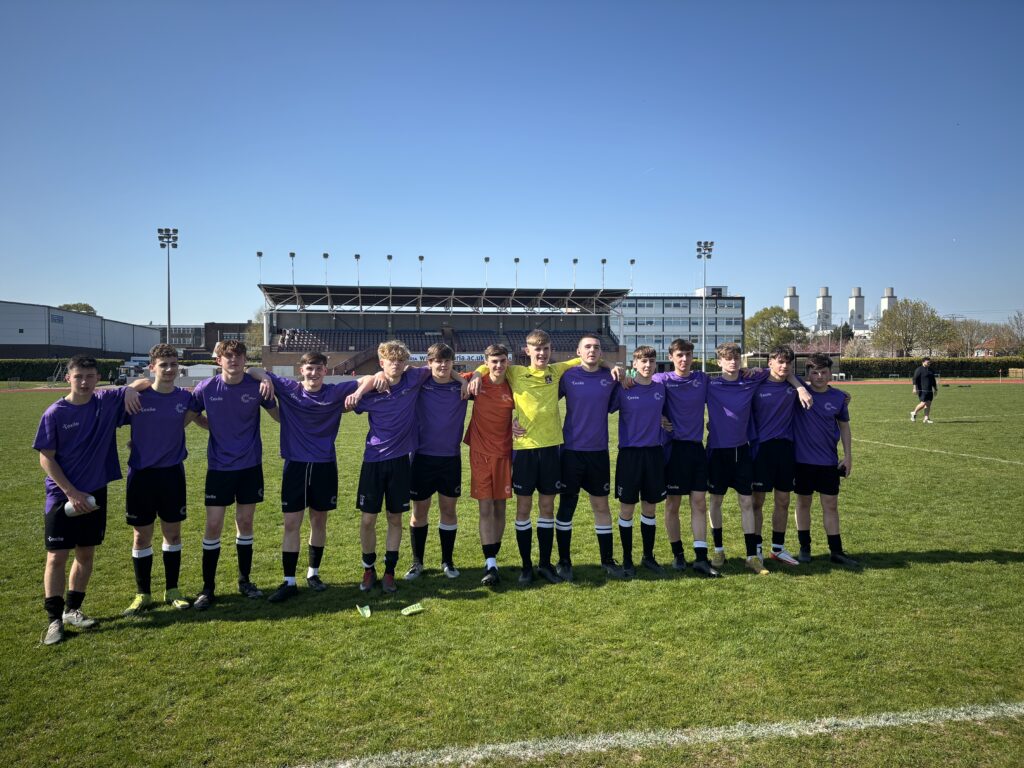 Coleg Cambria football team all standing on Deeside football stadium pitch in a line looking at the camera