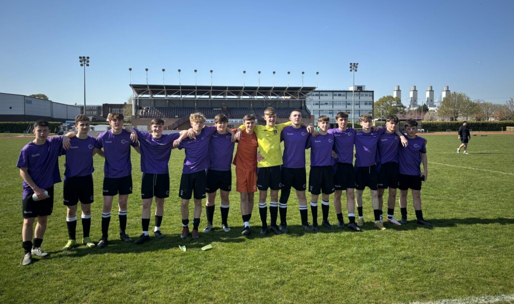 Coleg Cambria football team all standing on Deeside football stadium pitch in a line looking at the camera