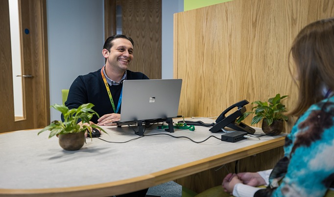 A student services officer smiling whilst speaking with a student at their desk in Yale