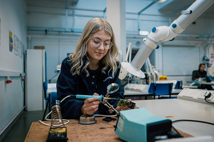 An apprentice in a workshop carefully working on a circuit