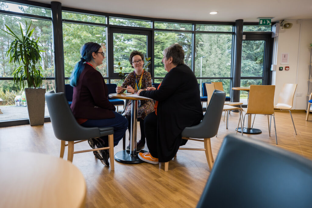 students and tutor sitting at table in Coleg Cambria Northop ILS building