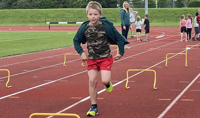A young boy running whilst taking part in Junior Athletics