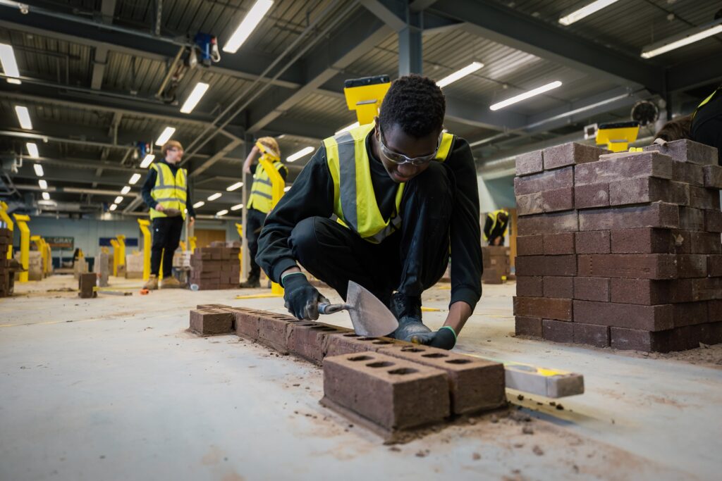 Brickwork student practicing laying bricks with two students behind