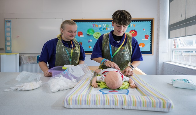 A childcare student practicing changing a toy baby's nappy