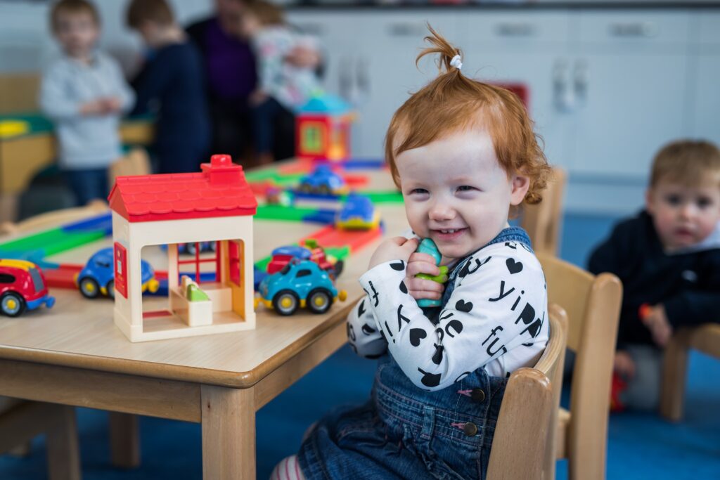 A happy young child in Toybox Nursery playing with toys