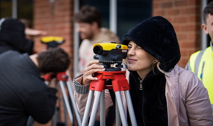 A HE student on a Construction course looking into a piece of construction equipment