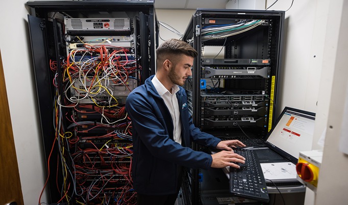 IT Apprentices working on a laptop with servers in the background