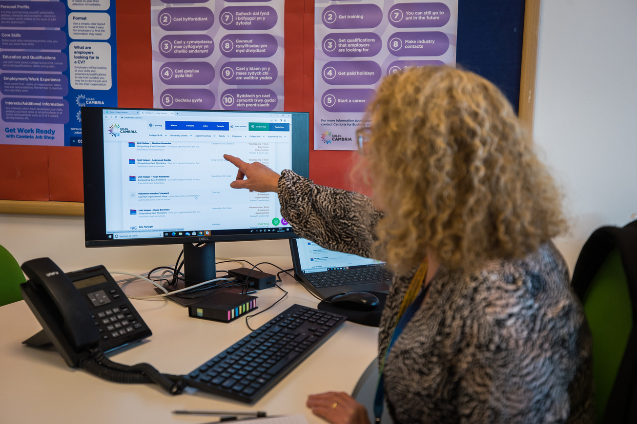 A member of The Job Shop team in Deeside pointing to a screen with job listings on