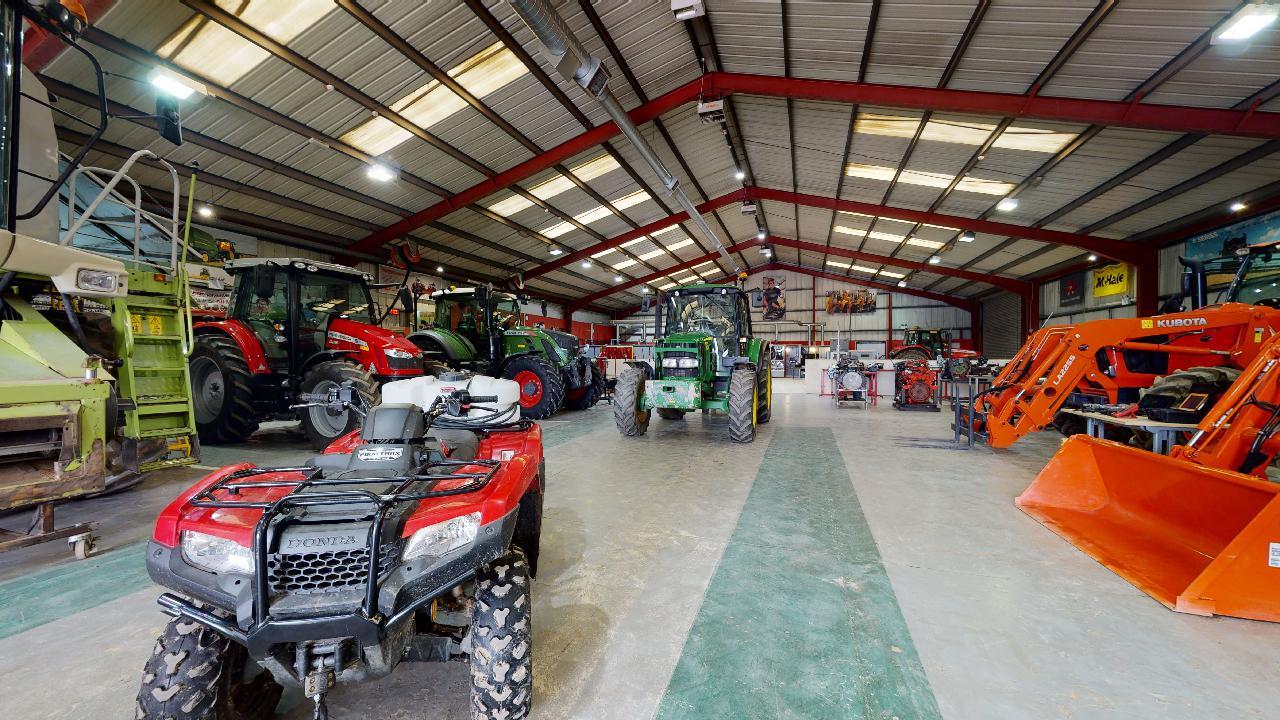 An image of agricultural vehicles, including tractors, quad bikes and harvesters inside a warehouse