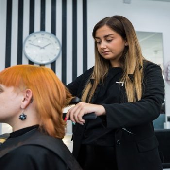 A hairdressing student cutting someone's hair in a salon